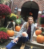 A student posing with four pumpkin sitting on concrete steps