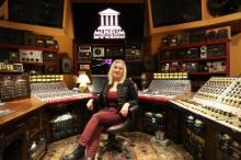 Sylvia Massy, sitting in a recording studio in a burgundy and black outfit