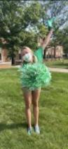 A student cheering with a green pom pom and spirit finger