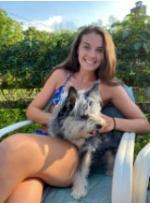 Sarah Beck sits outdoors with a dog on her lap