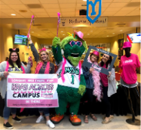 A group of sorority sisters take a group photo with Screamer while holding a sign reading bras across campus