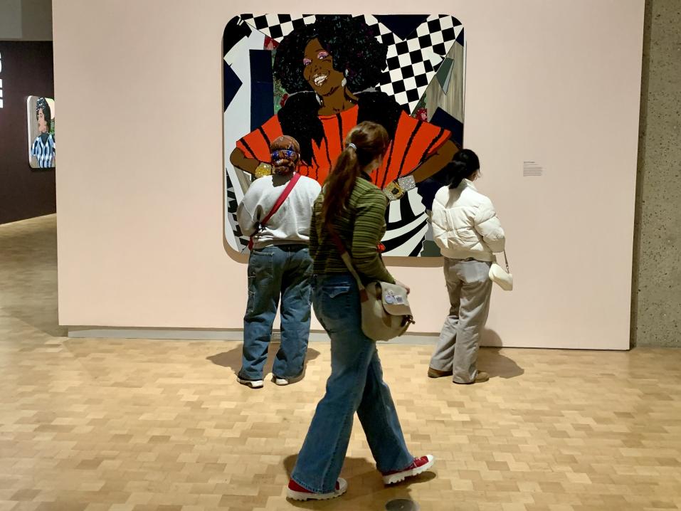 A woman can be seen admiring artwork at a museum with her back to the camera