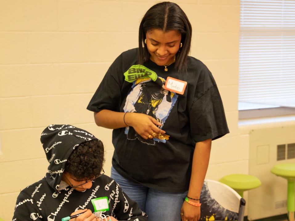 Merelys de la Cruz Guzman works with a person on a craft