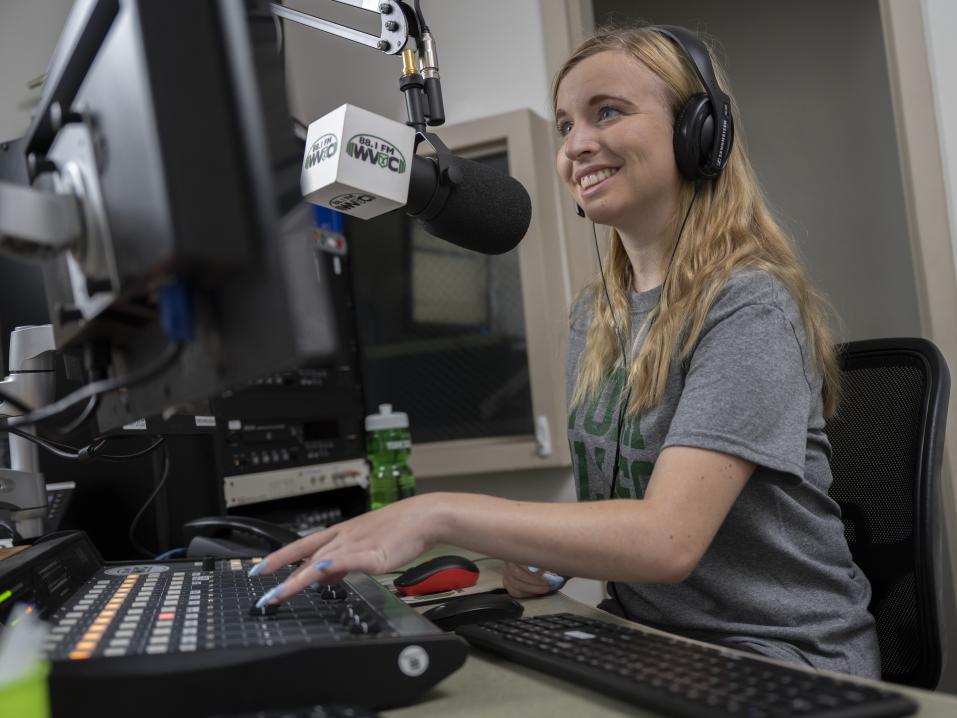 A student in front of a large microphone sitting at a computer.