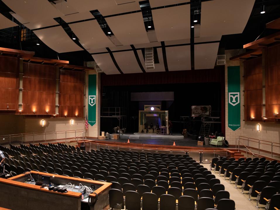 A large empty theater with green banners on either side of the stage.