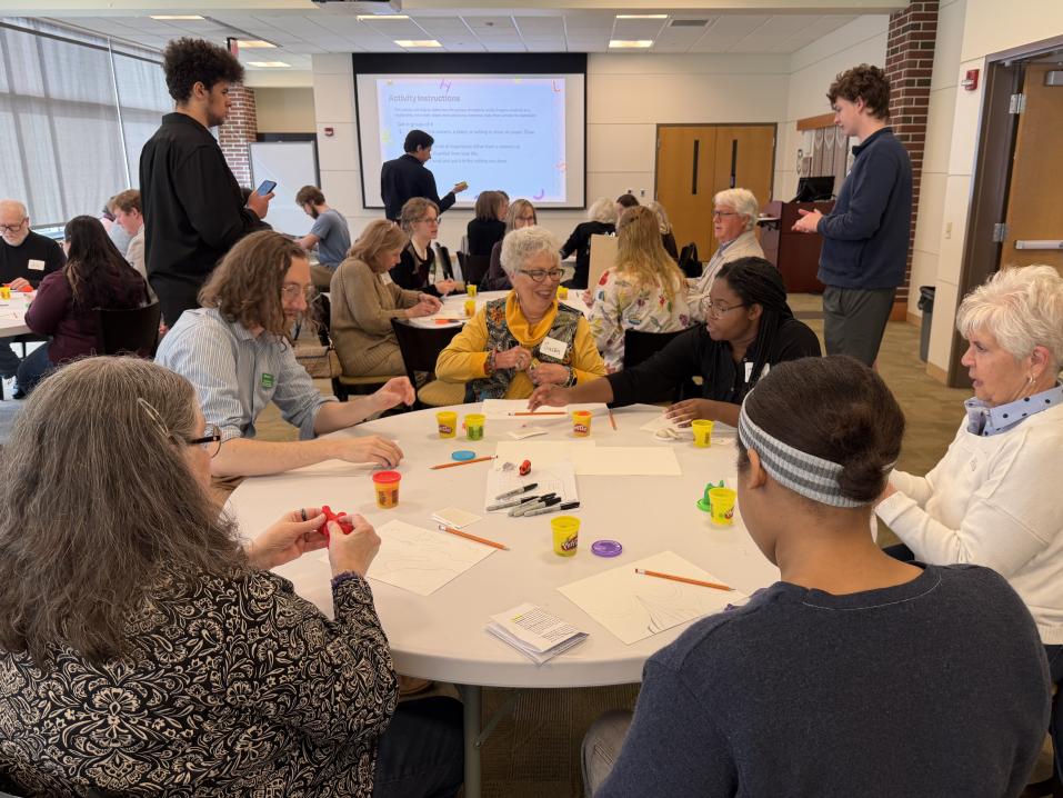 A busy classroom with LLI Students working together at tables with YCP Students.