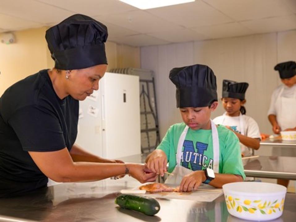 Liz Morales, the founder of Cooking Up Connection, demonstrating cooking techniques to a program participant.