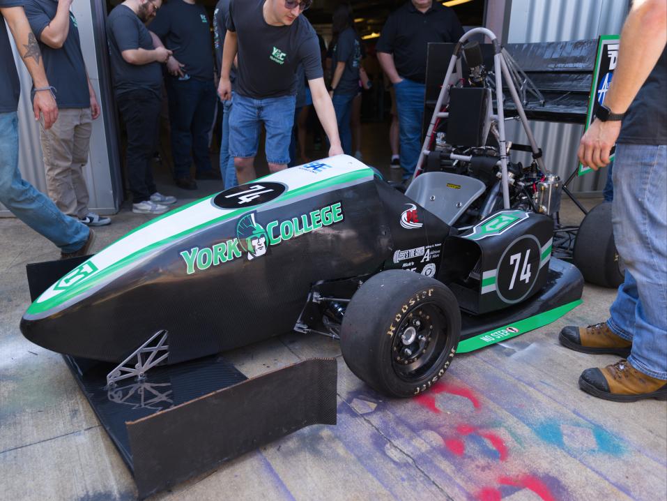 Students showcase a Formula SAE race car at a college engineering event.