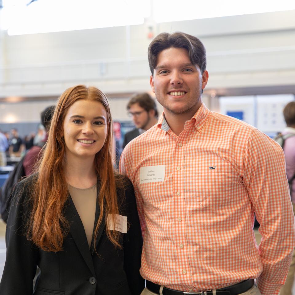 Two students in professional attire smile at the camera at the YCP Career Expo.