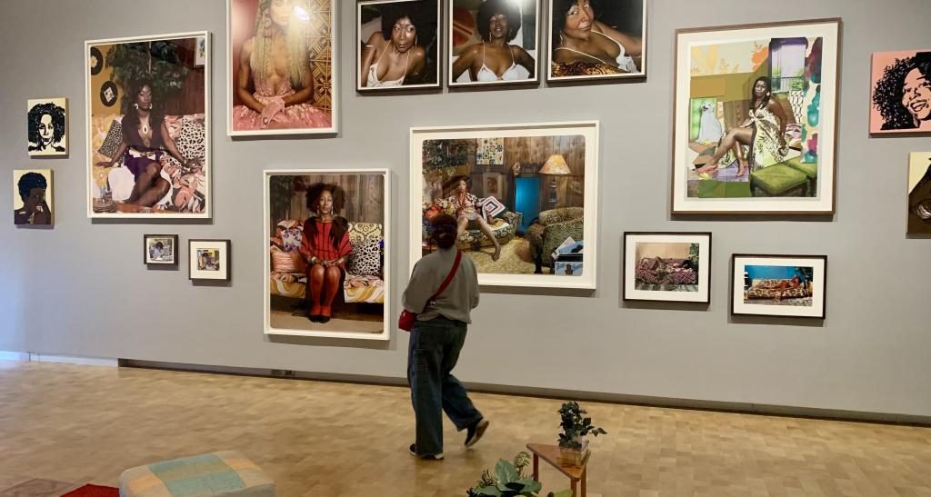 A person walking with their back to the camera facing a wall of artwork