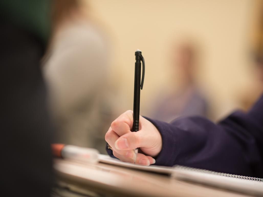 A student using a pencil to write on a piece of paper.