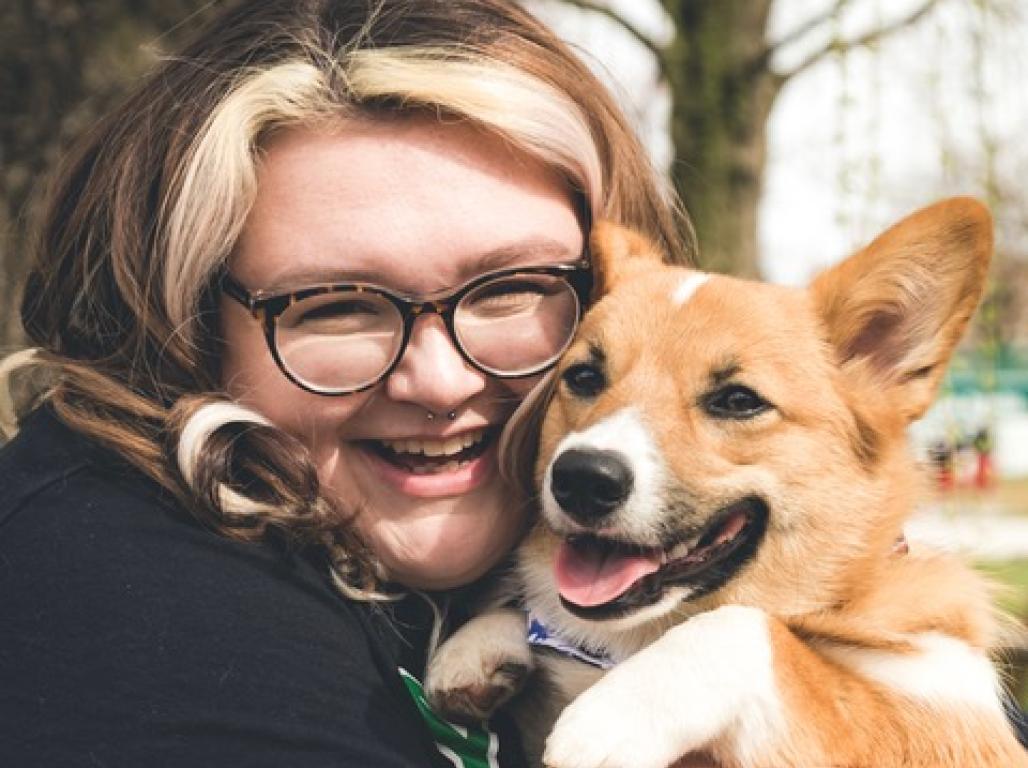 Person smiling while holding a dog.