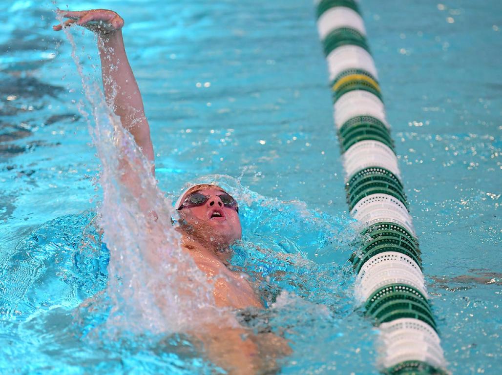 A man is swimming the backstroke in the pool