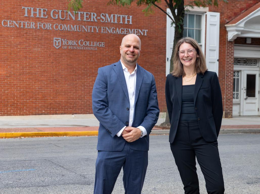 Jeff Vermeulen & Carly Legg Wood stand back to back in front of the CCE building
