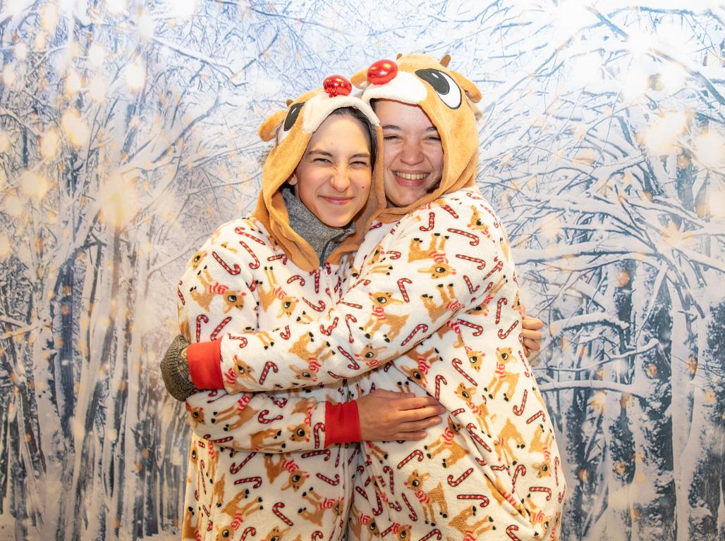 Two students in festive attire posing in front of a winter-themed backdrop.