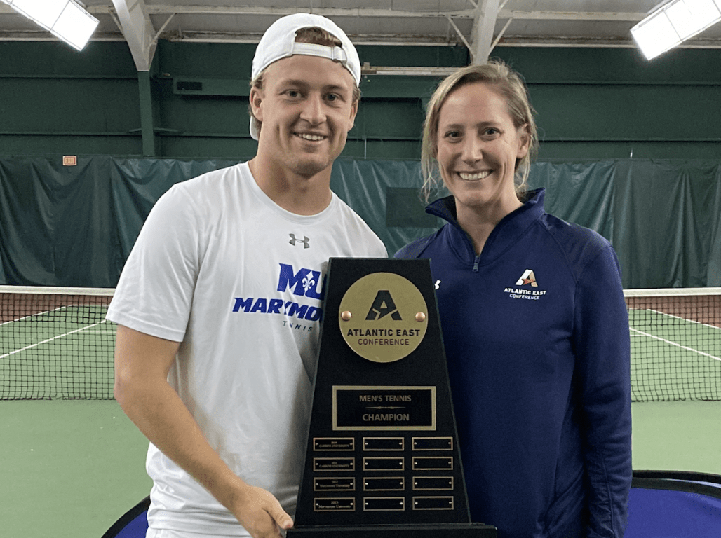 Two people pose with an award in an indoor athletic facility.