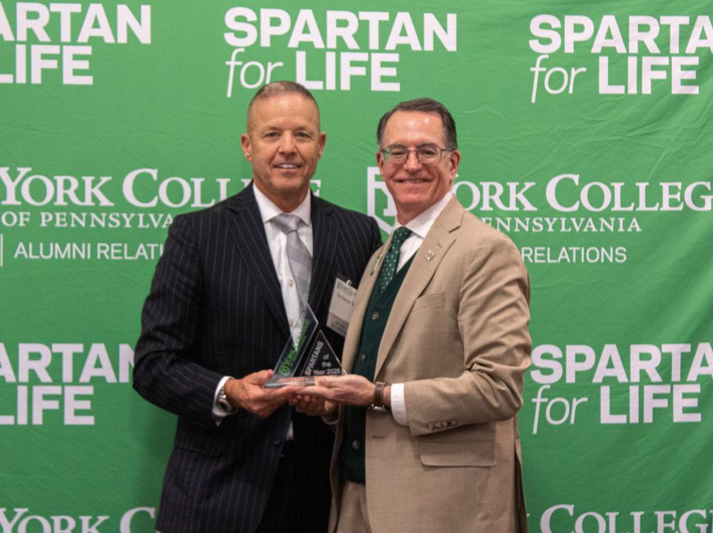 Tim Kerner stands with President Burns holding an award for Spartan of the Year.
