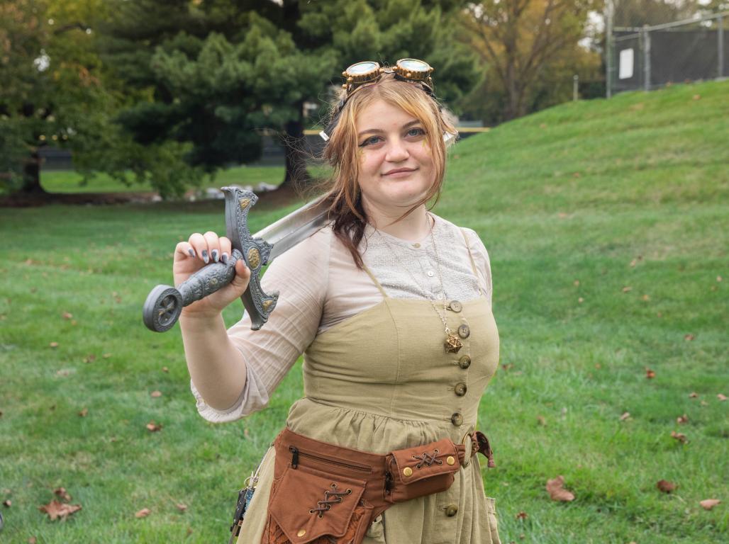 Person in a costume with a sword smiles at the camera.