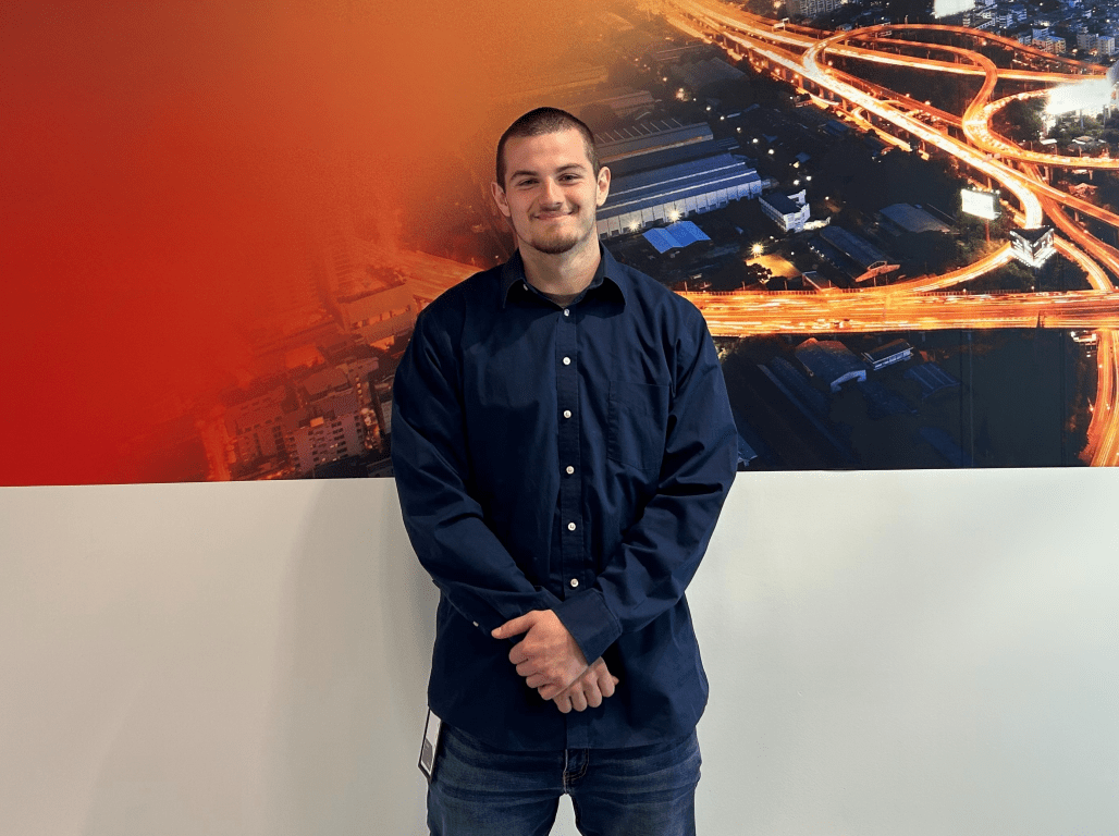 Mechanical Engineering major Gavin Wentz poses in front of a wall decorated with a cityscape graphic.