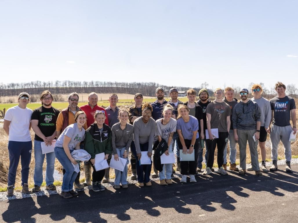 A group of civil engineering students pose for a photo in an outdoor setting. Some are wearing York College shirts.
