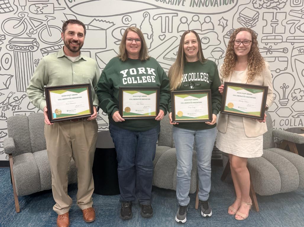 Four people stand in front of a GCCI Mural holding awards.