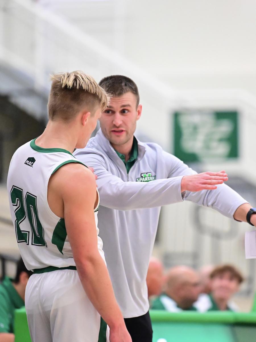 Jared Wagner stands with a player giving directions on the basketball court