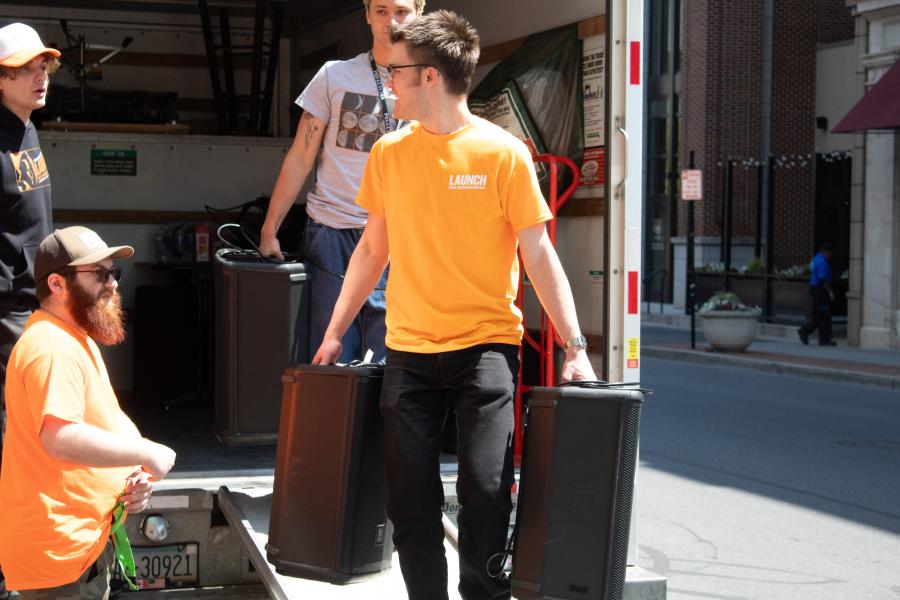 A group of people unloading audio equipment from a truck.