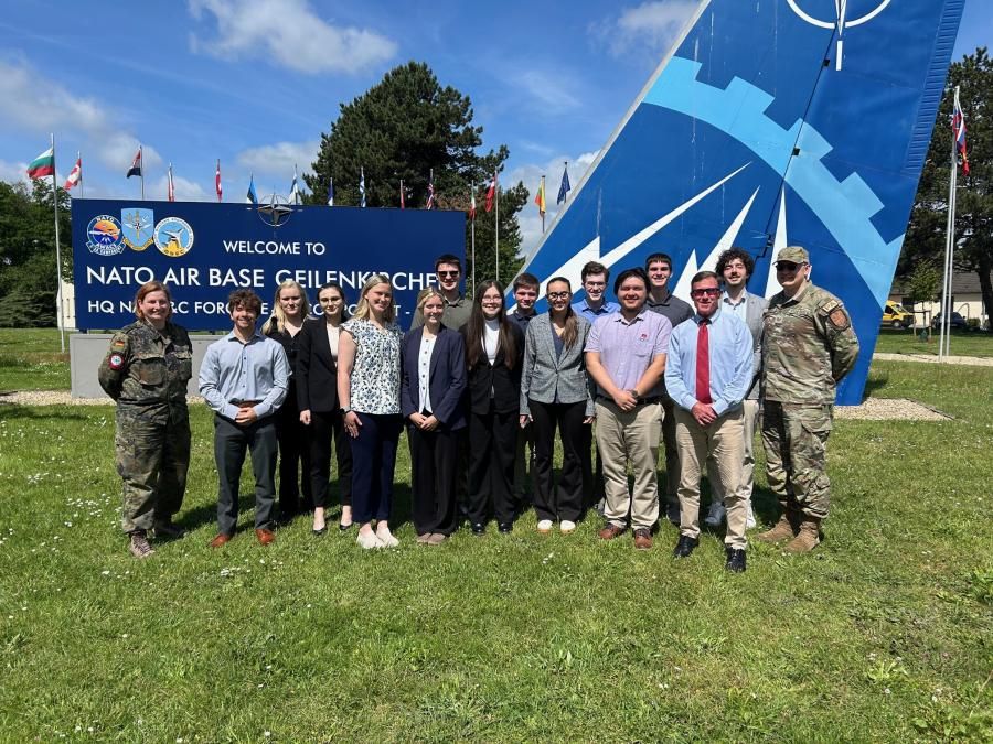 Students post in front of the NATO sign in professional clothing.