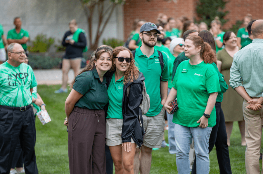 York College students and employees wearing green pose and gather together outside during National College Colors Day.