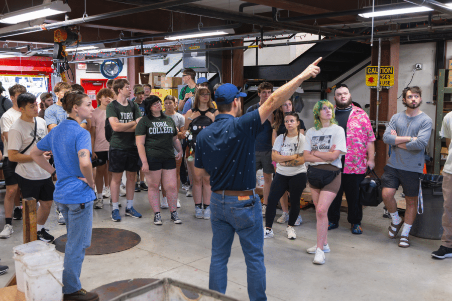 York College Civil Engineering students listen as a Hersheypark engineer explains ride systems inside a maintenance and operations area.
