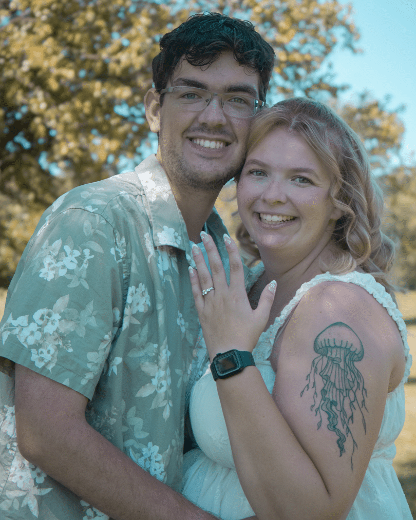 Khora Pawelczyk ’26 smiles with her fiancé outdoors while showing her engagement ring.