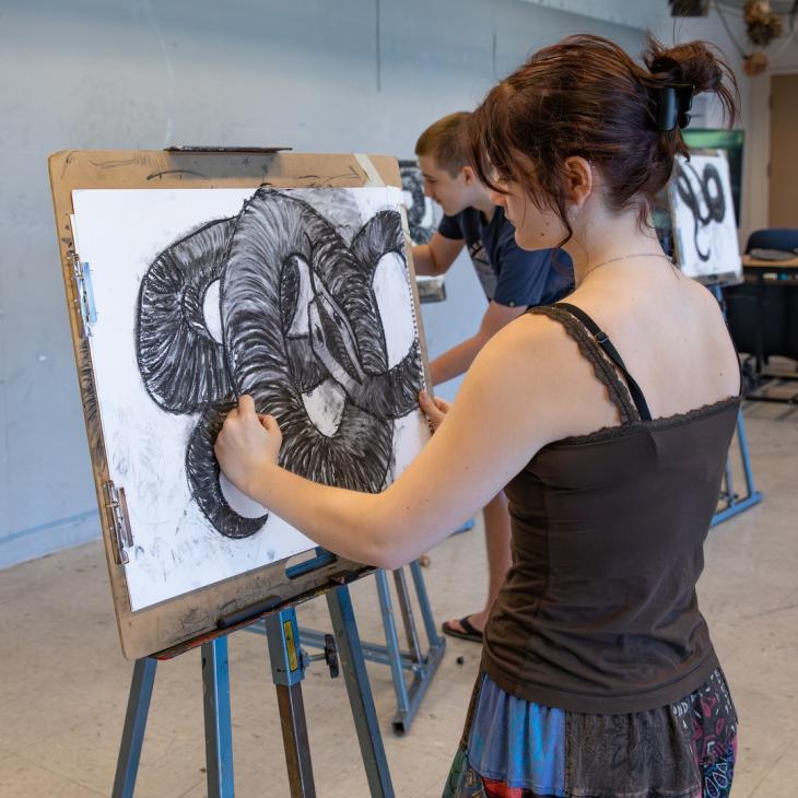 A student works on an art piece with her back to the camera