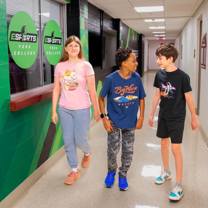 Three student walk in the hallway outside of ESports