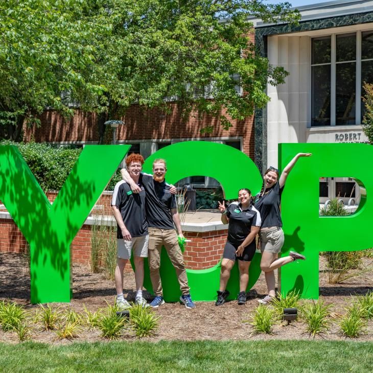 Four students posing in from of the large green YCP letters