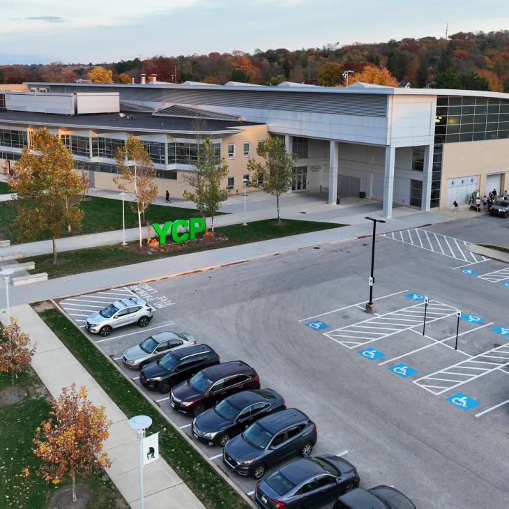 An aerial view of a parking lot with the YCP green letters in front of the Grumbacher Center.