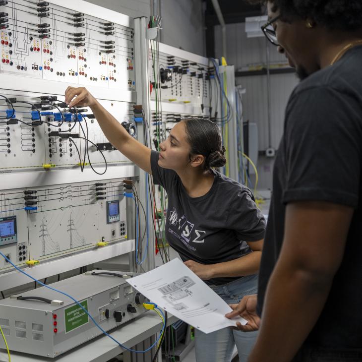 Two students work on a circuit board.