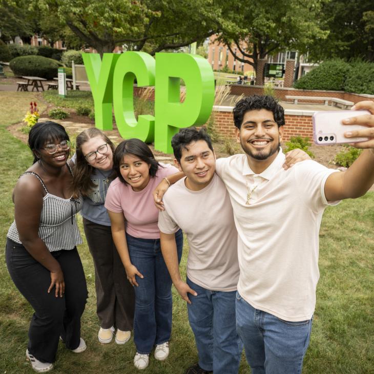 A group of students posing for a selfie at the YCP letters.